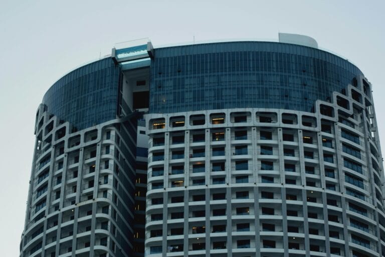 A modern high-rise building with a rooftop infinity pool extending beyond the edge