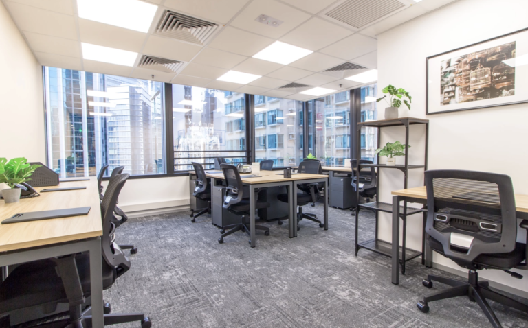 Bright modern coworking space with city views, ergonomic chairs, wooden desks, and large windows.